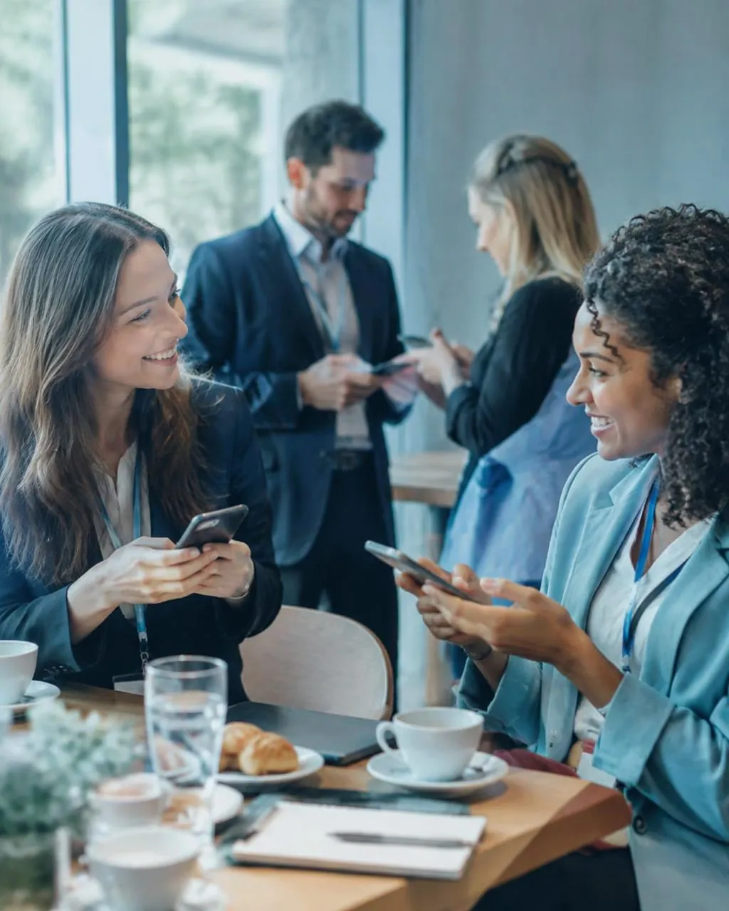 Empreendedoras trocando contatos pelo celular em um café da manhã de networking